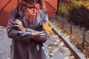 Young beautiful woman with umbrella posing outside at fall time